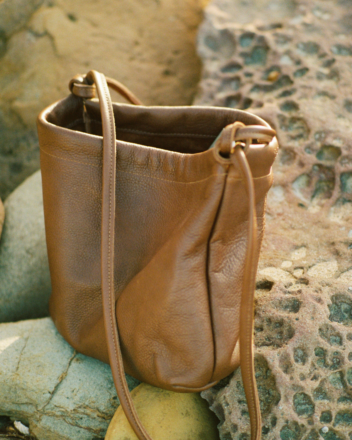 a brown leather handbag on beach rocks