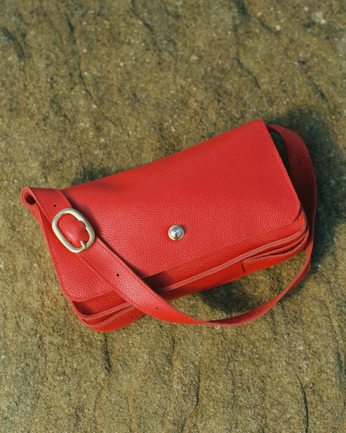 a red purse on a rock surface