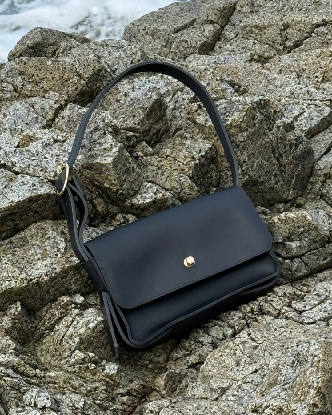 a black purse against a rock
