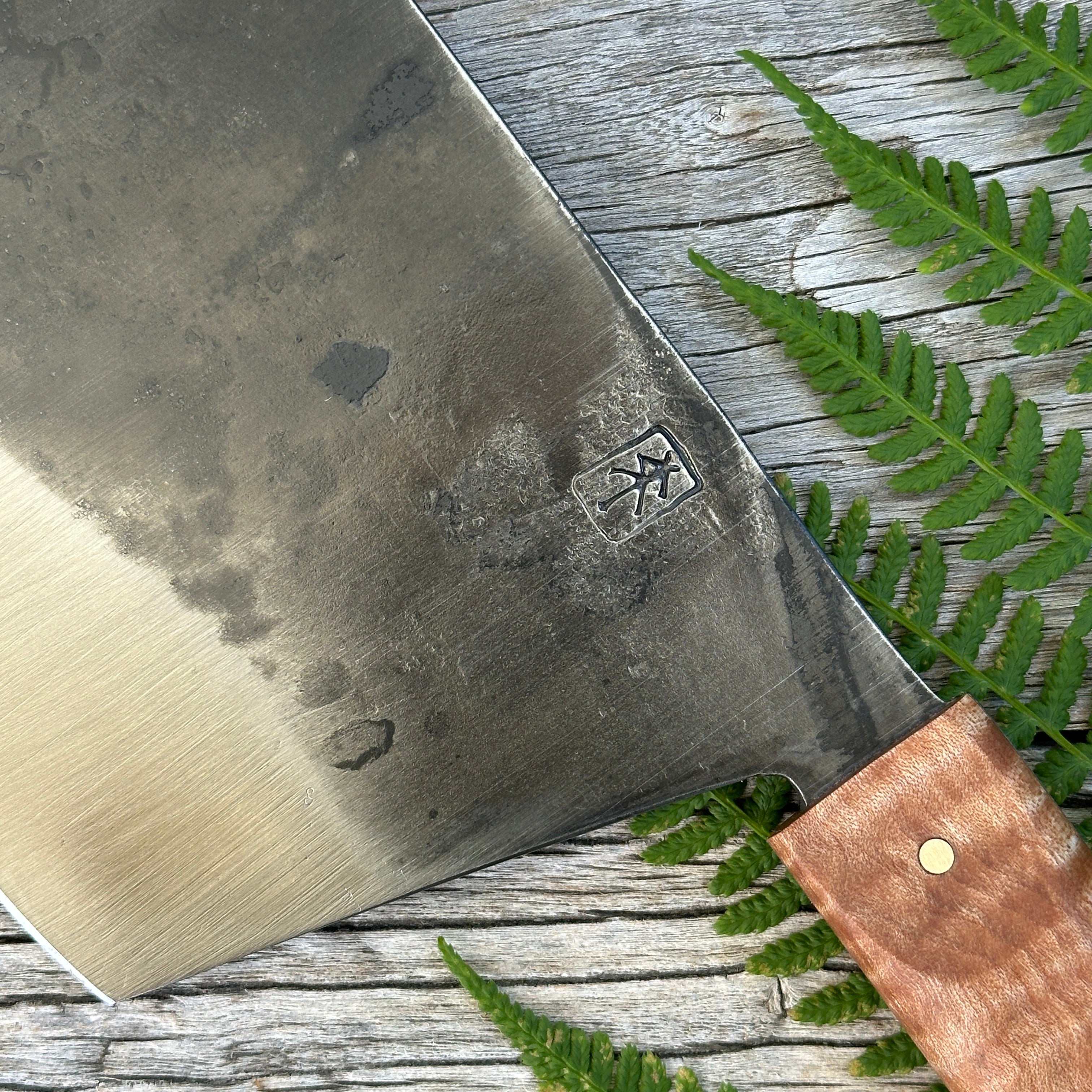 Leechtown Blacksmith Co. for Confluence Nimmo Bay knife with a wooden handle on a wooden surface with green leaves