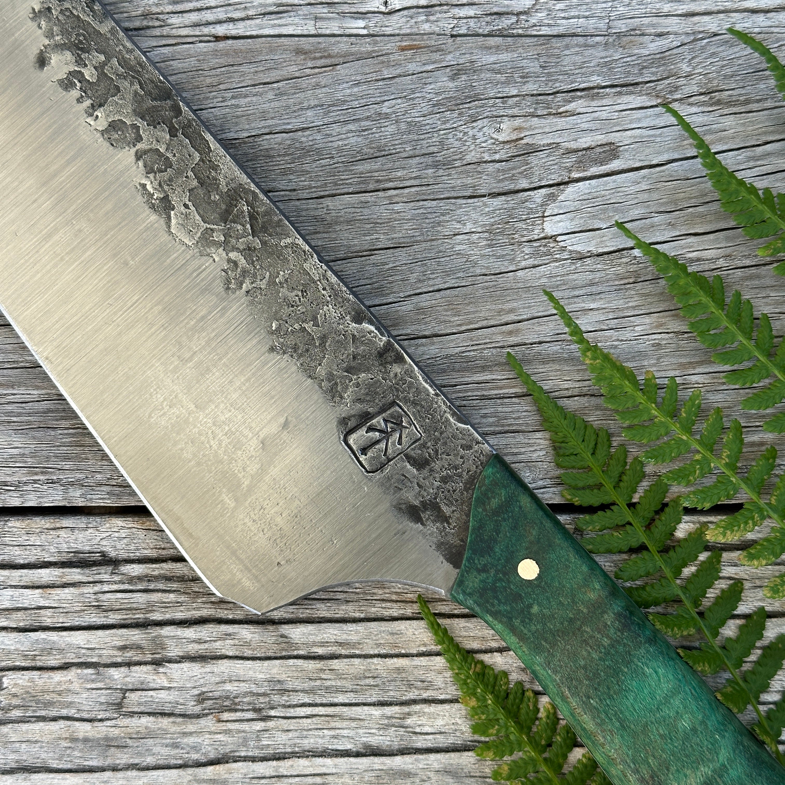 Leechtown Blacksmith Co. for Confluence Nimmo Bay knife with a green handle on a wooden surface with fern leaves
