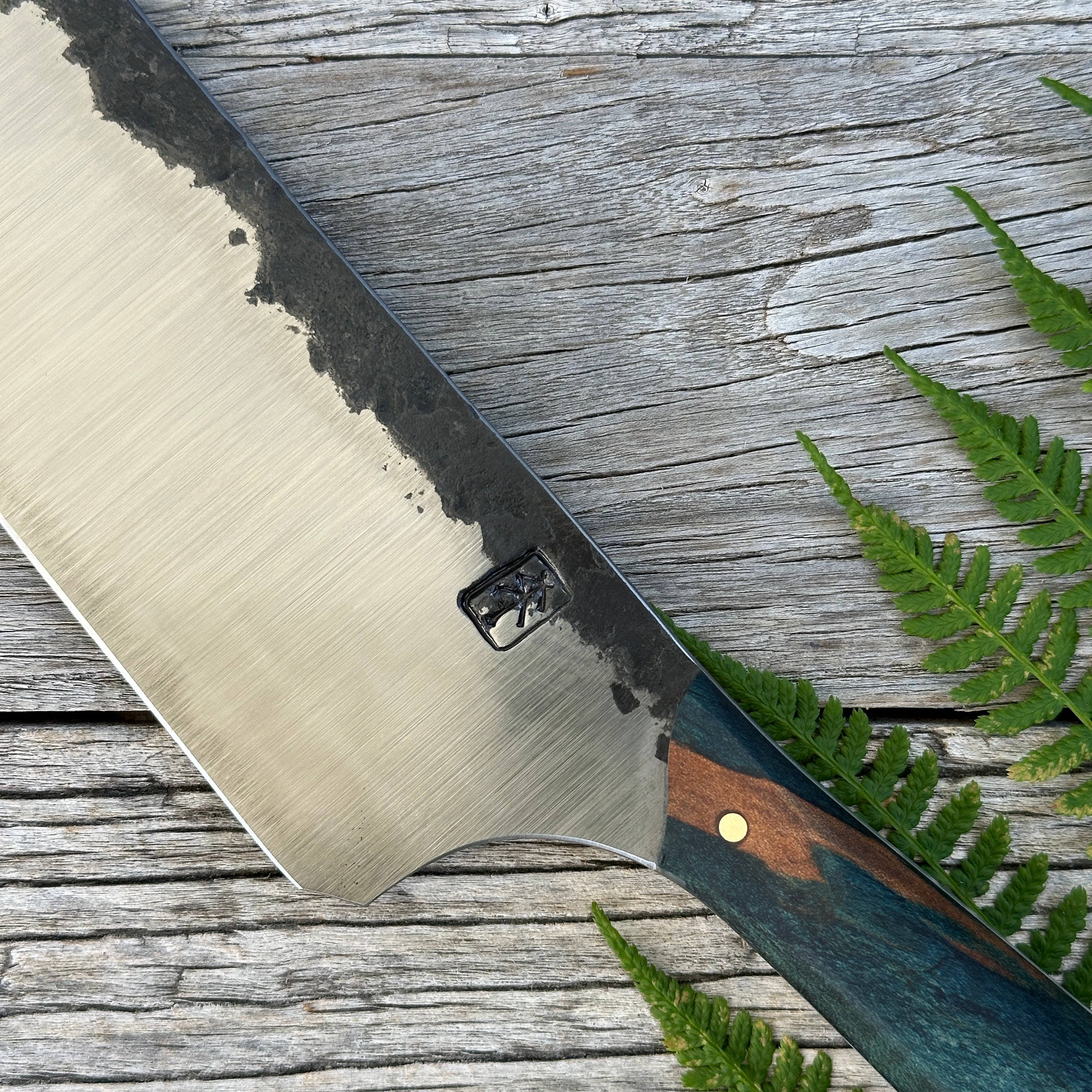 Leechtown Blacksmith Co. for Confluence Nimmo Bay knife with a wooden handle on a wooden surface with ferns
