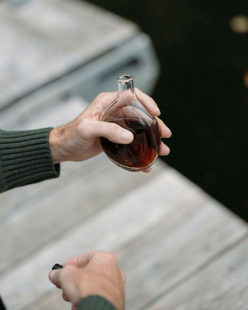Person holding a Goodbeast glass flask with against a water background