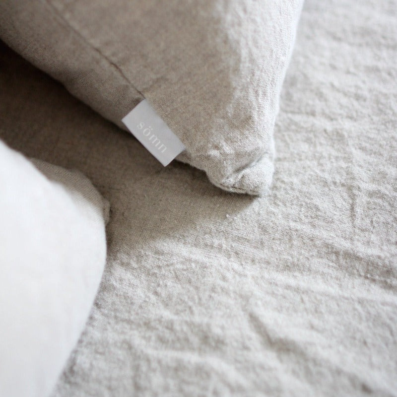Textured gray pillow with a brand label on a matching fabric background