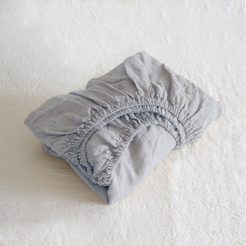 Folded gray fitted sheet on a white surface