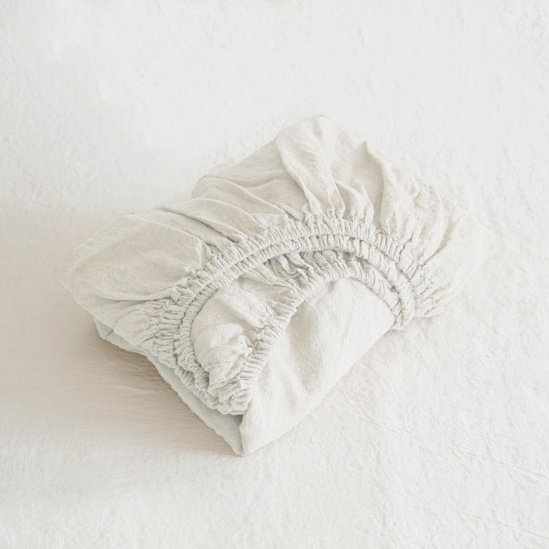 White fitted sheet on a bed with a plain background