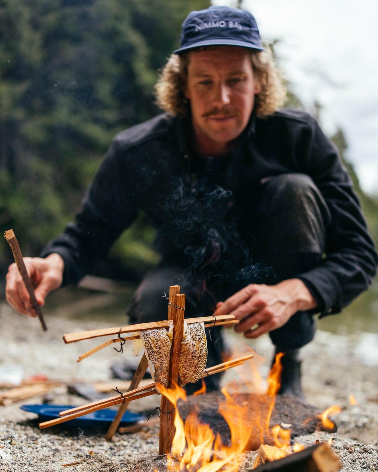 man cooking fish onn a fire