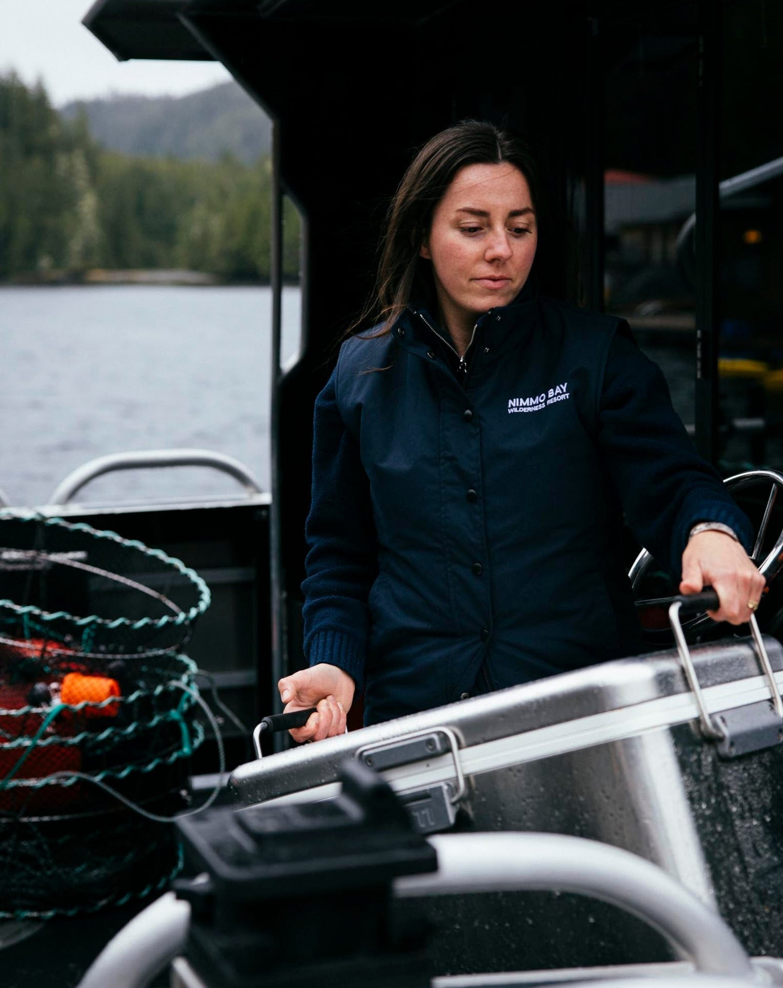 Nimmo Bay x Anian women's double lofted vest on a woman carrying a yeti cooler off a boat