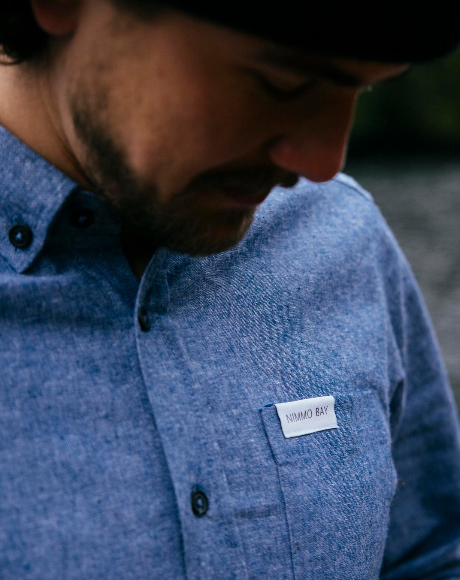 Nimmo Bay x Anian long sleeve blue chambray shirt. Man lookind down