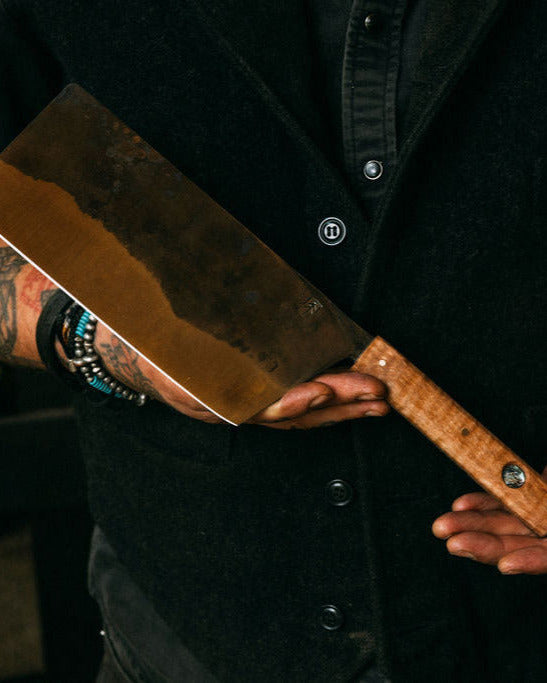 Person holding a large cleaver with a dark background