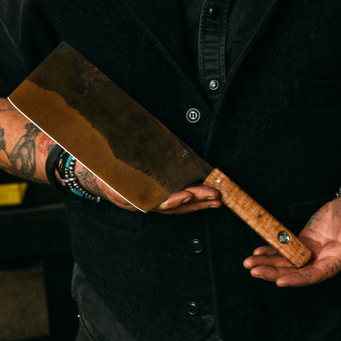 Person holding a large cleaver with a dark background