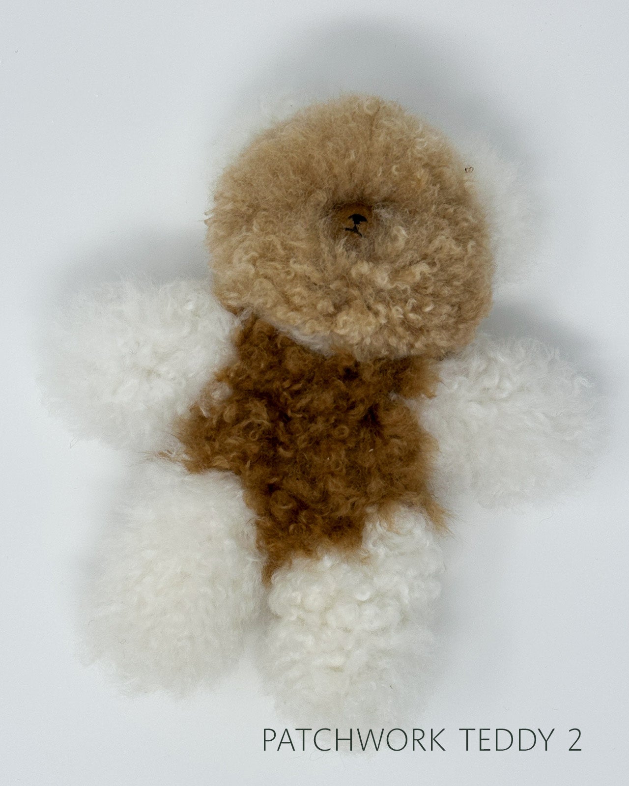 Patchwork teddy bear with brown and white fur on a light gray background