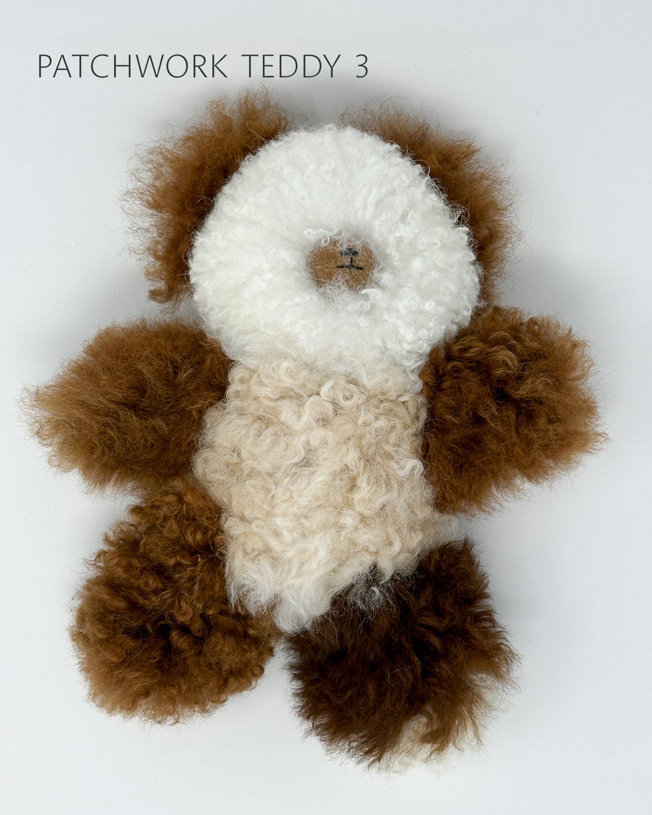 Patchwork teddy bear with brown and white fur on a light gray background