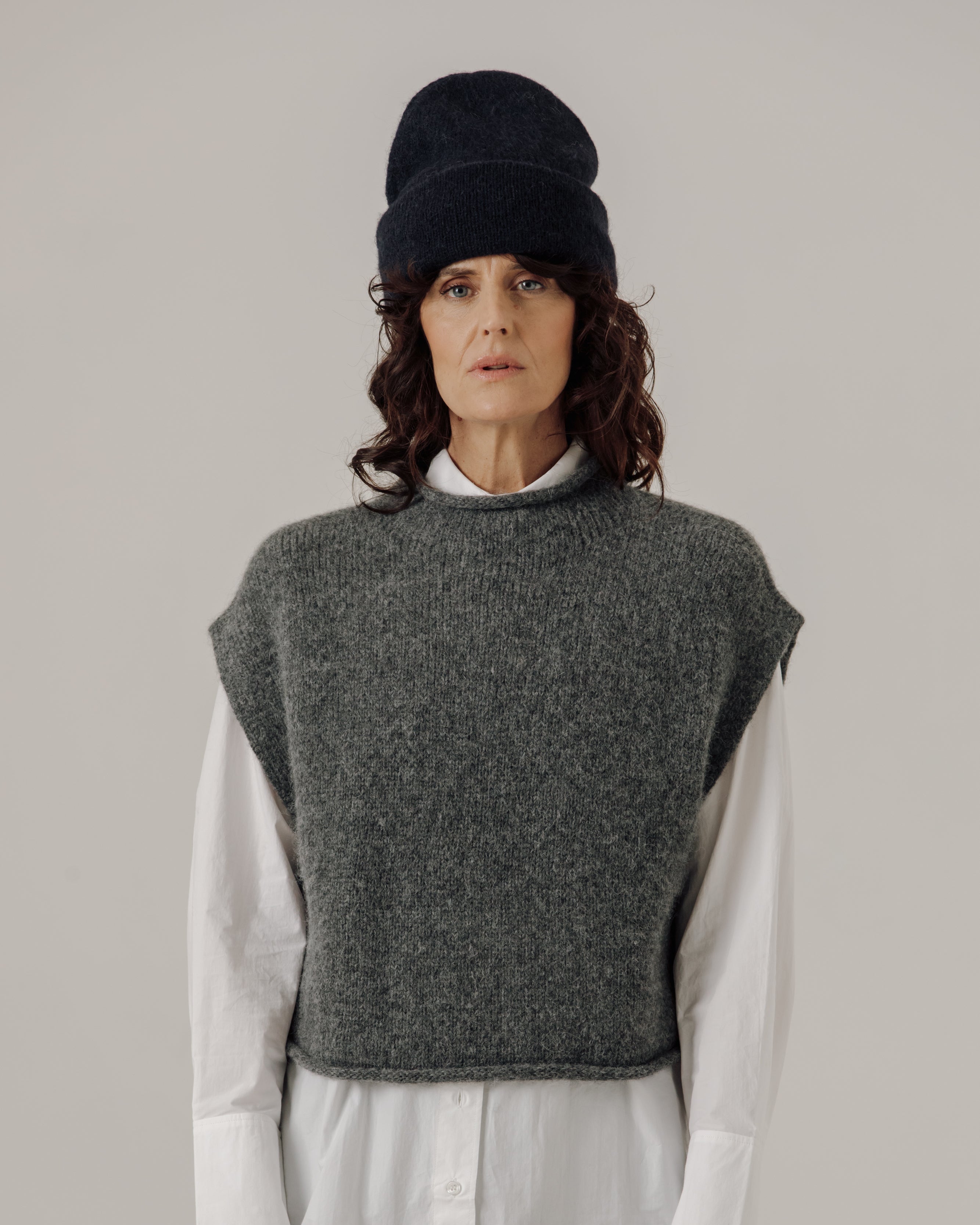 woman wearing a navy beanie in front of a white background