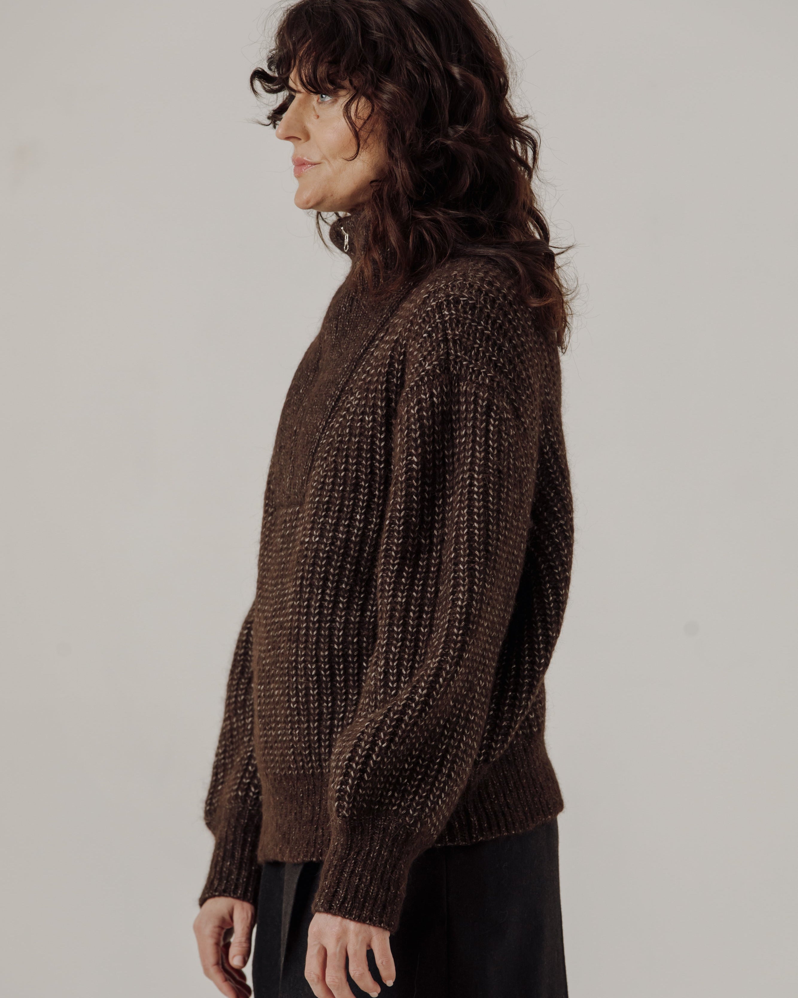 Woman wearing a brown knitted sweater against a plain background