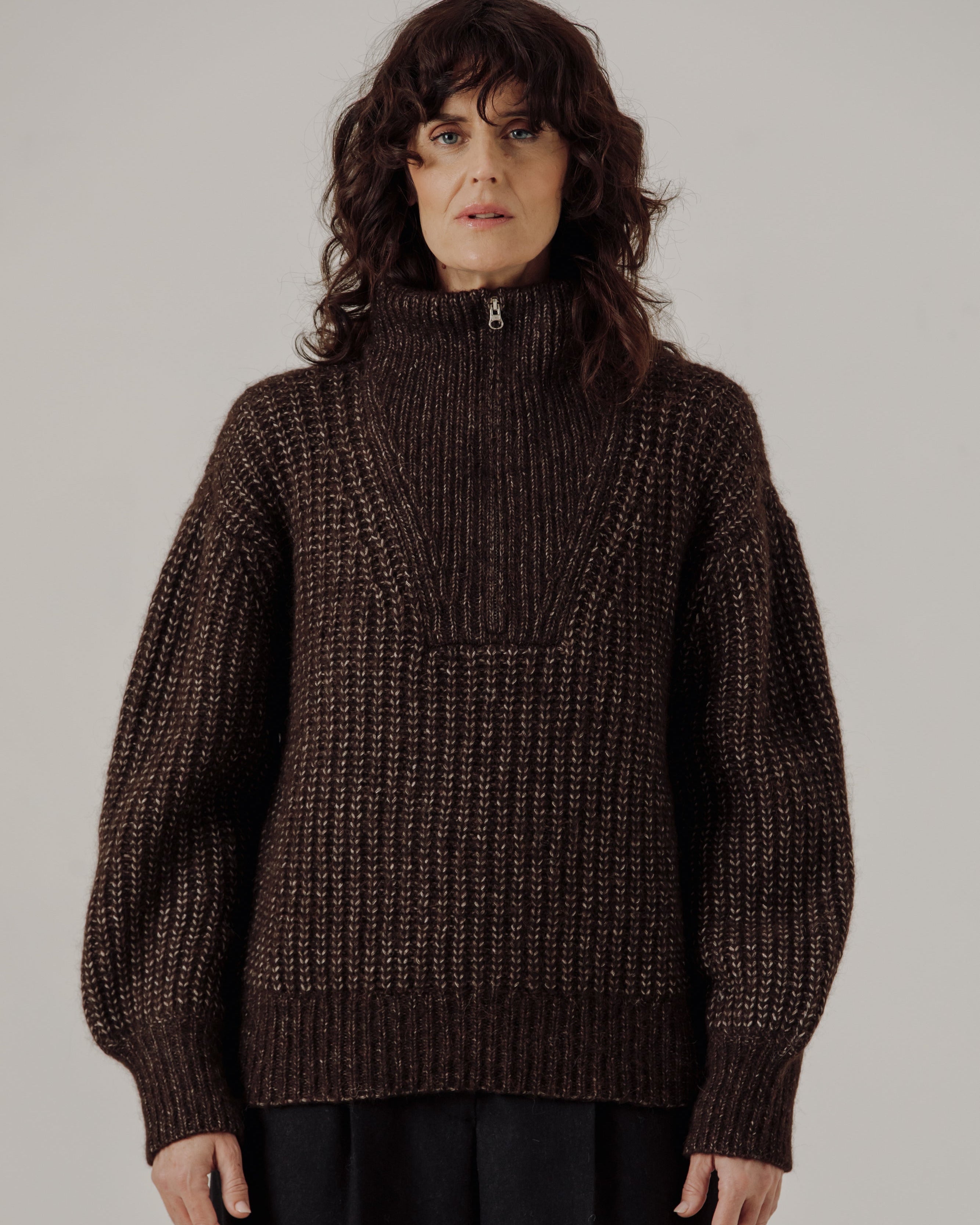 Person wearing a Bare Knitwear Alpine Quarter Zip Sweater in Carob against a plain background