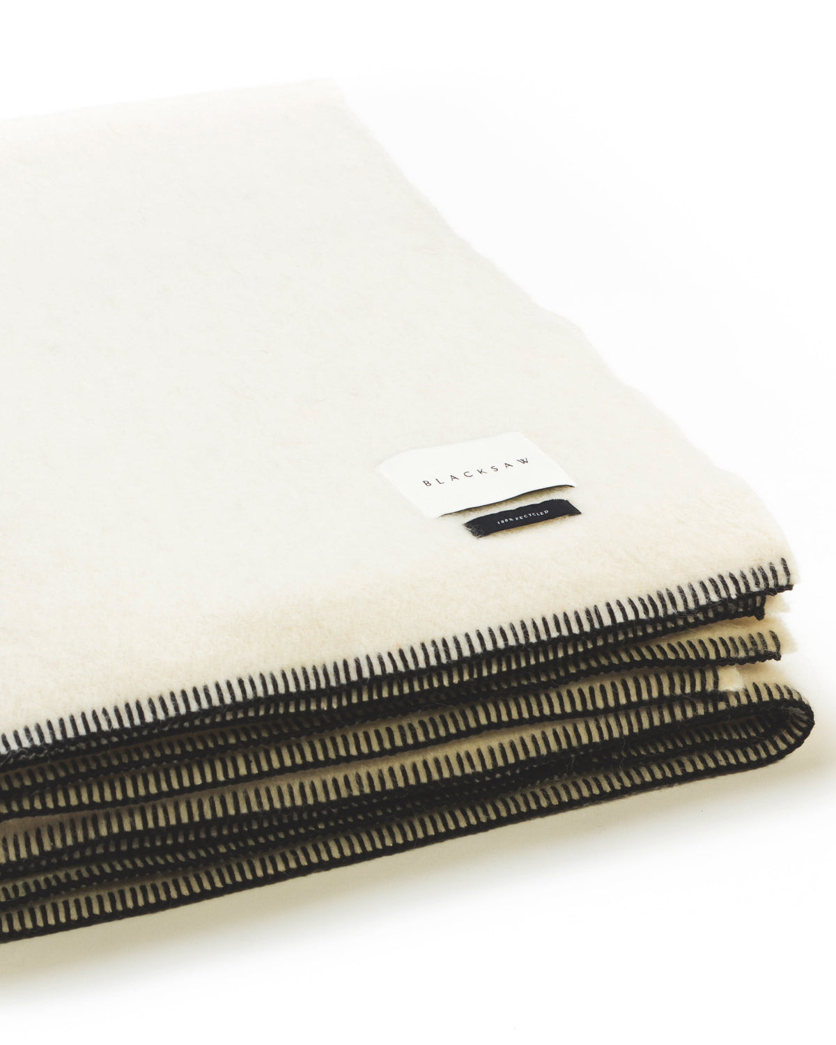 Folded white blanket with black trim on a white background