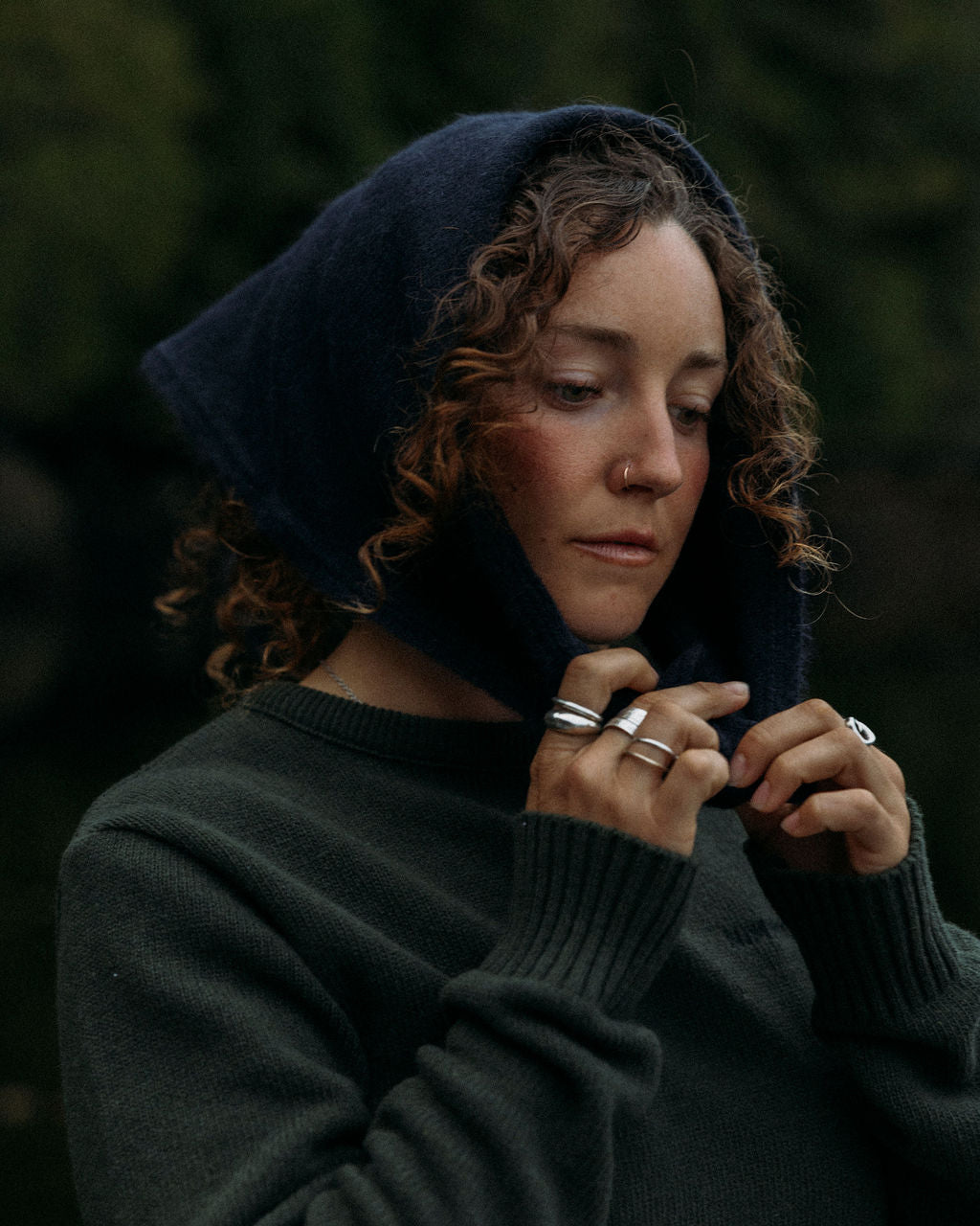 Person wearing a navy blue Bare Knitwear bandana and green fisherman sweater with a blurred background