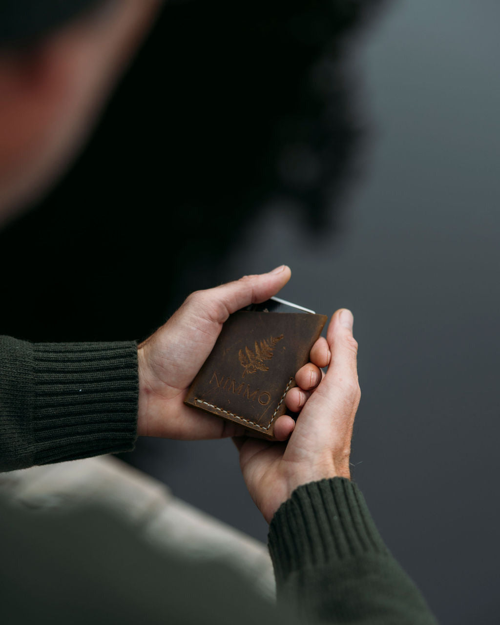 Person holding a brown leather wallet with a blurred background