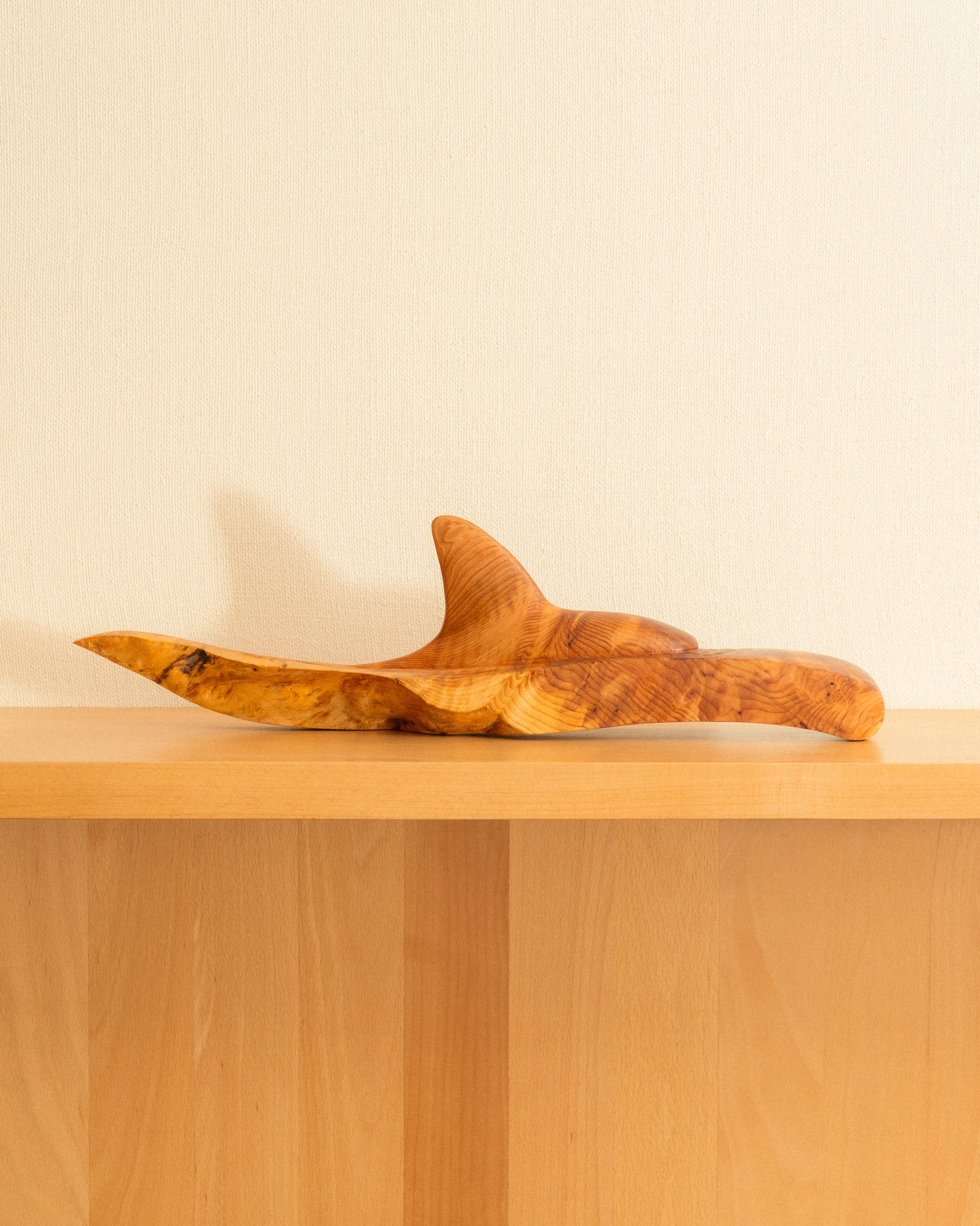 Wooden Orca carving on a wooden surface with a plain background