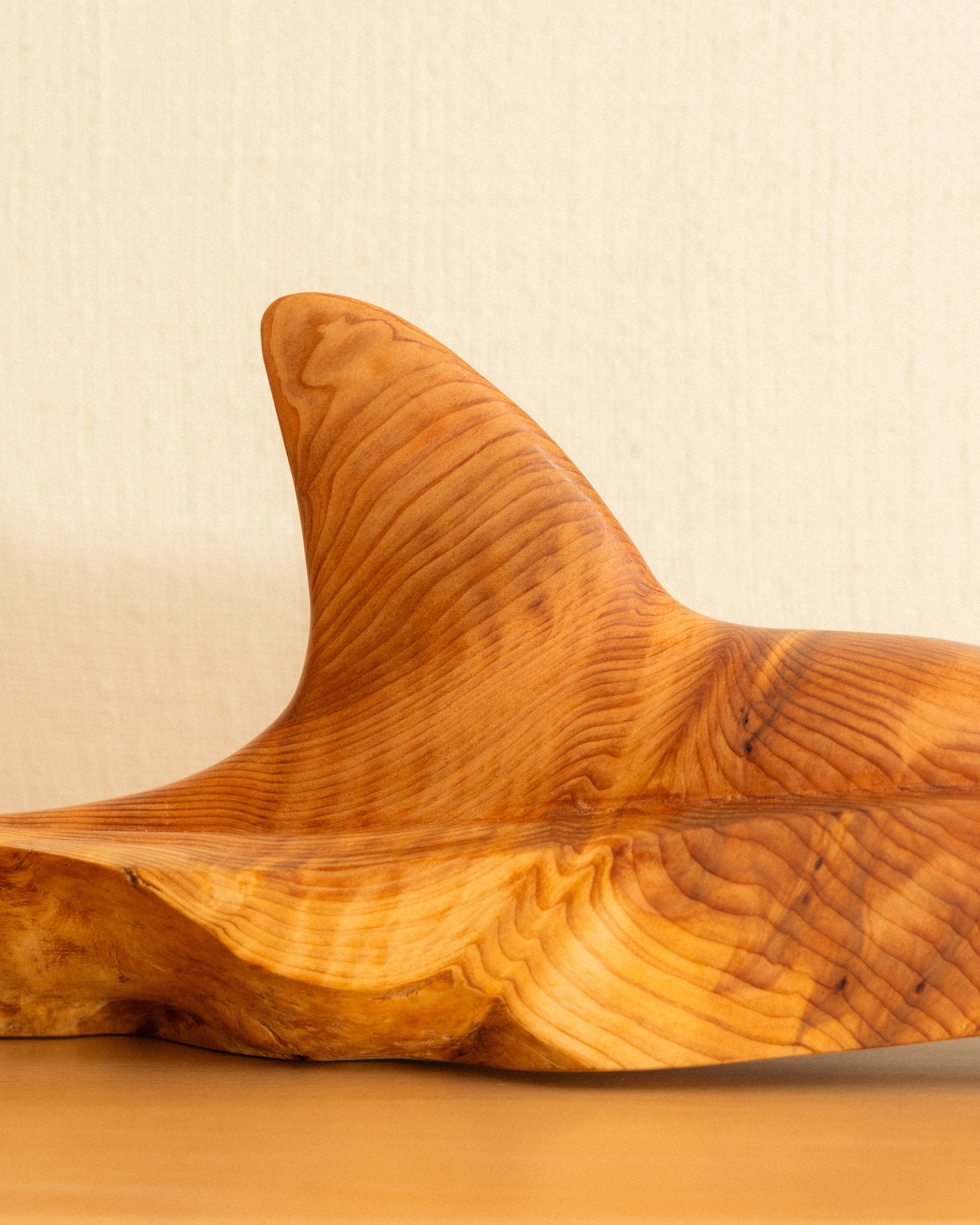 Wooden Orca fin carving on a beige background