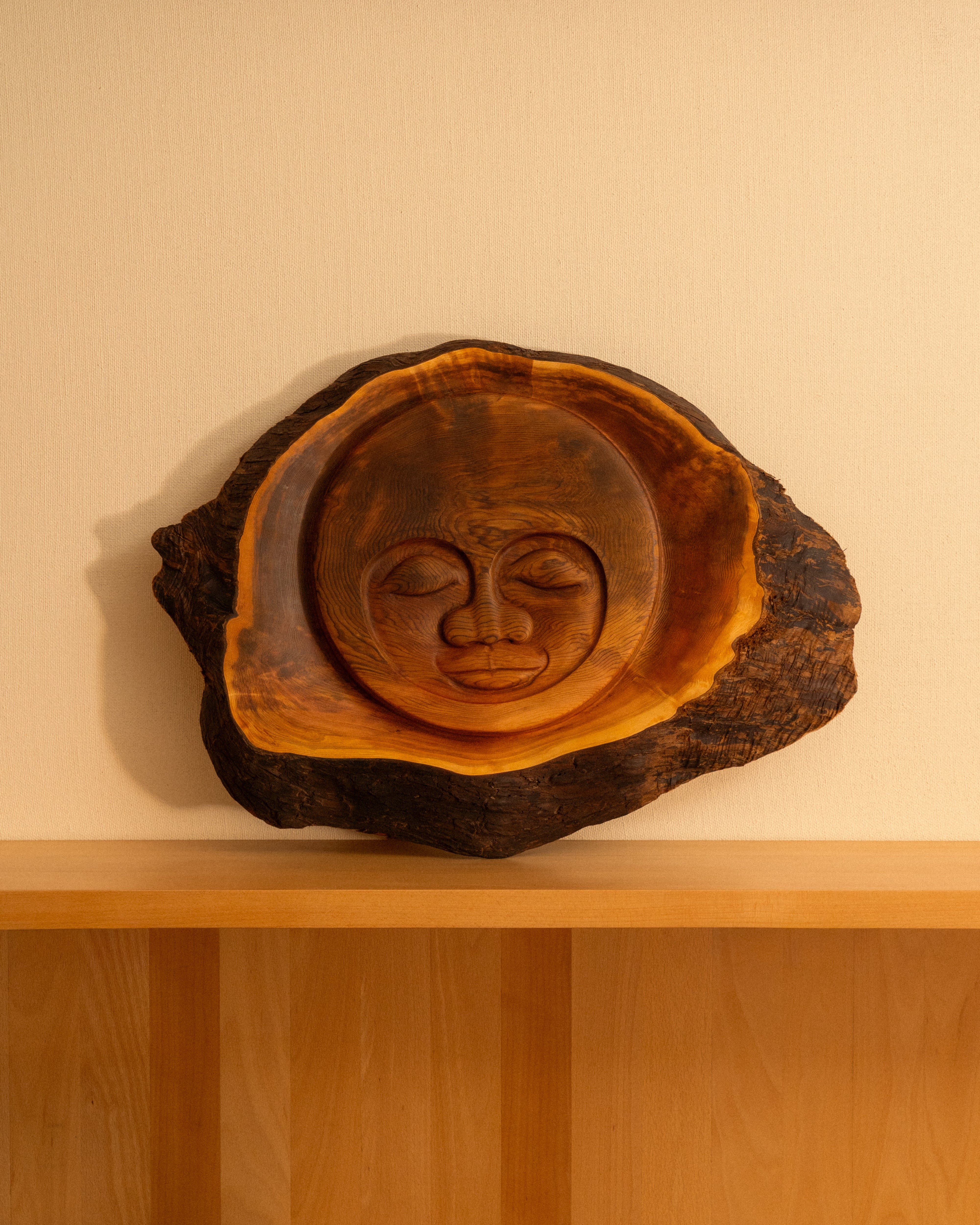 large wooden cedar sun face carvings against a neutral background.