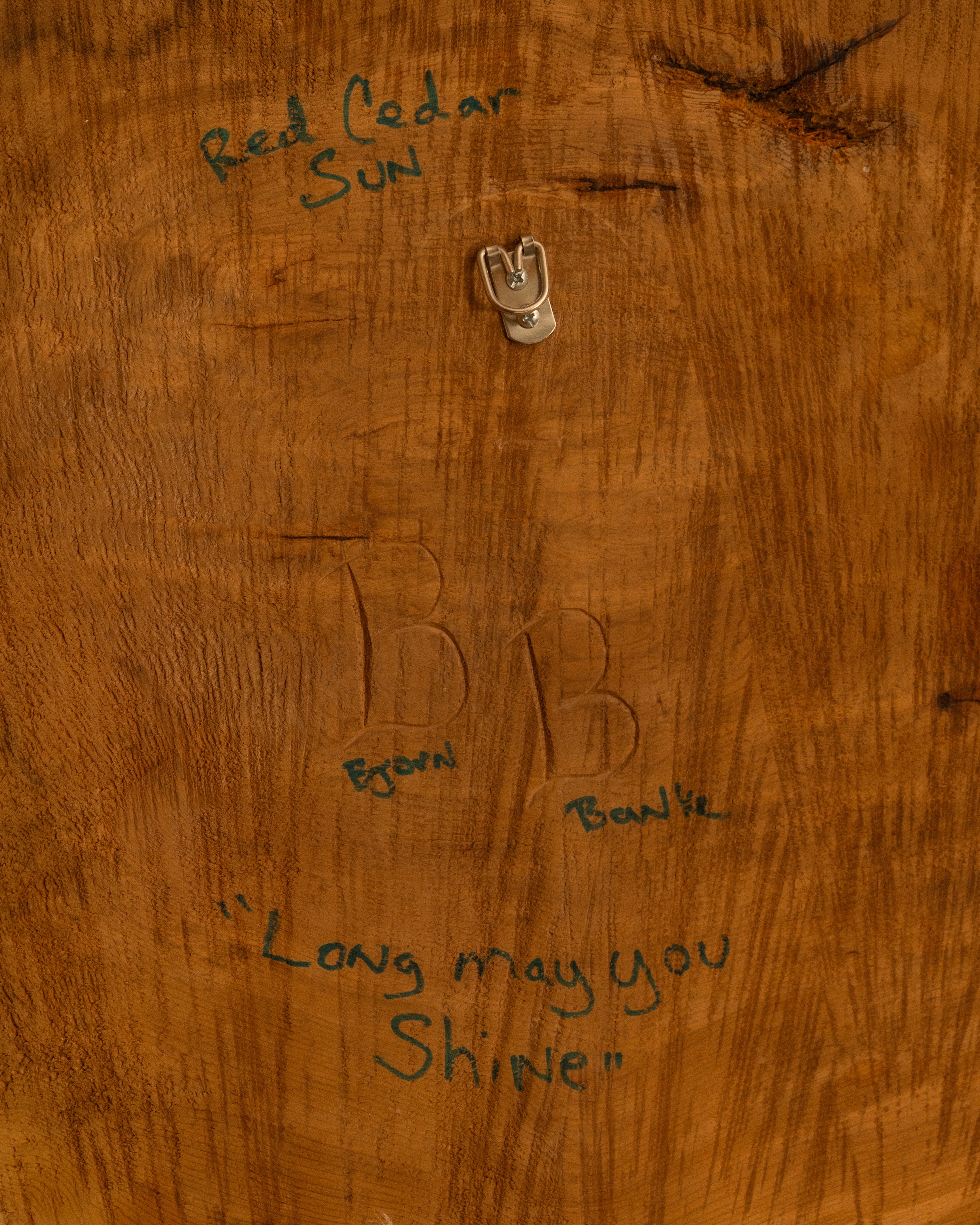 Wooden surface with engraved initials and text "Long may you shine"