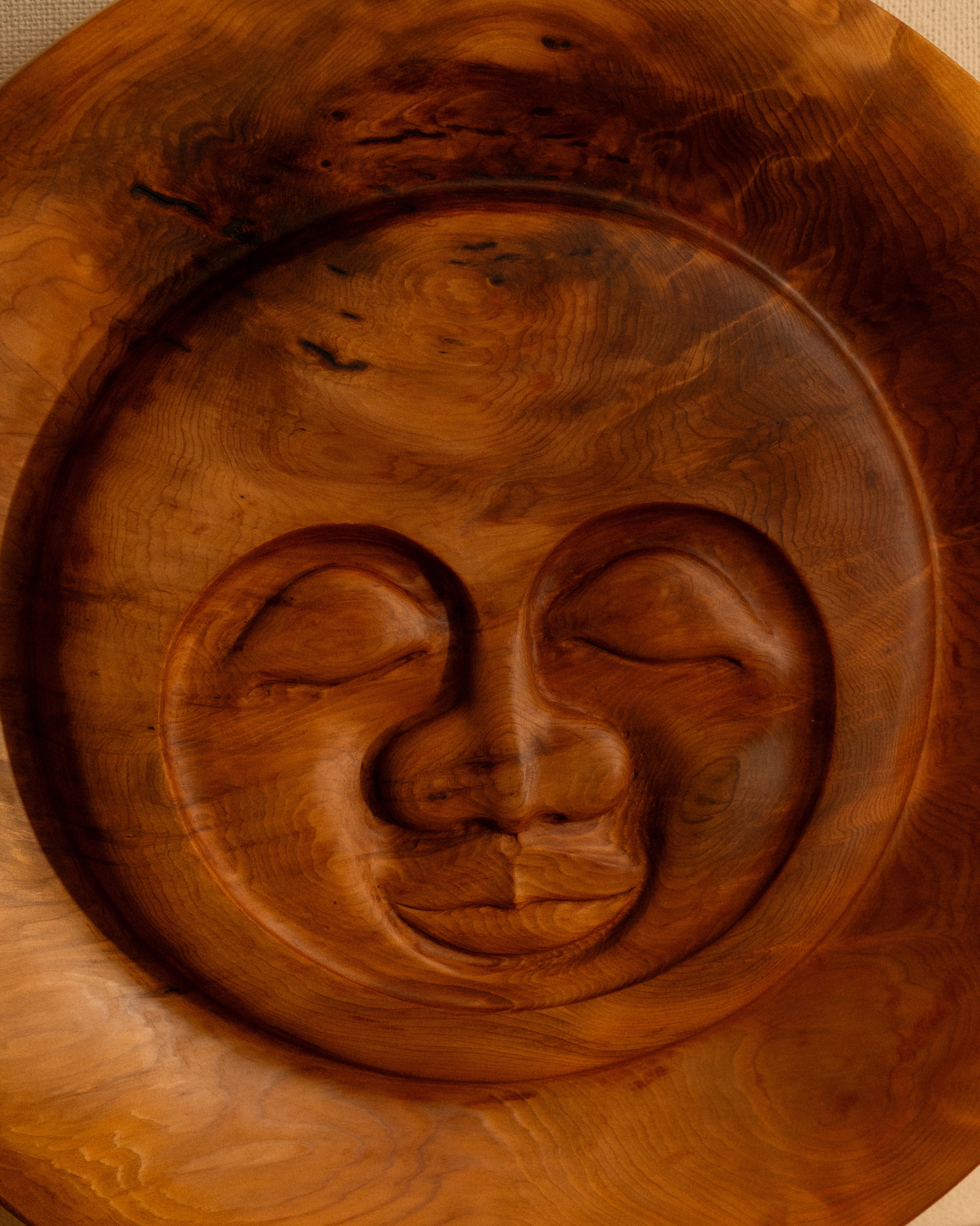 Serenity Sun carving by Bjorn Banke on a wooden shelf.