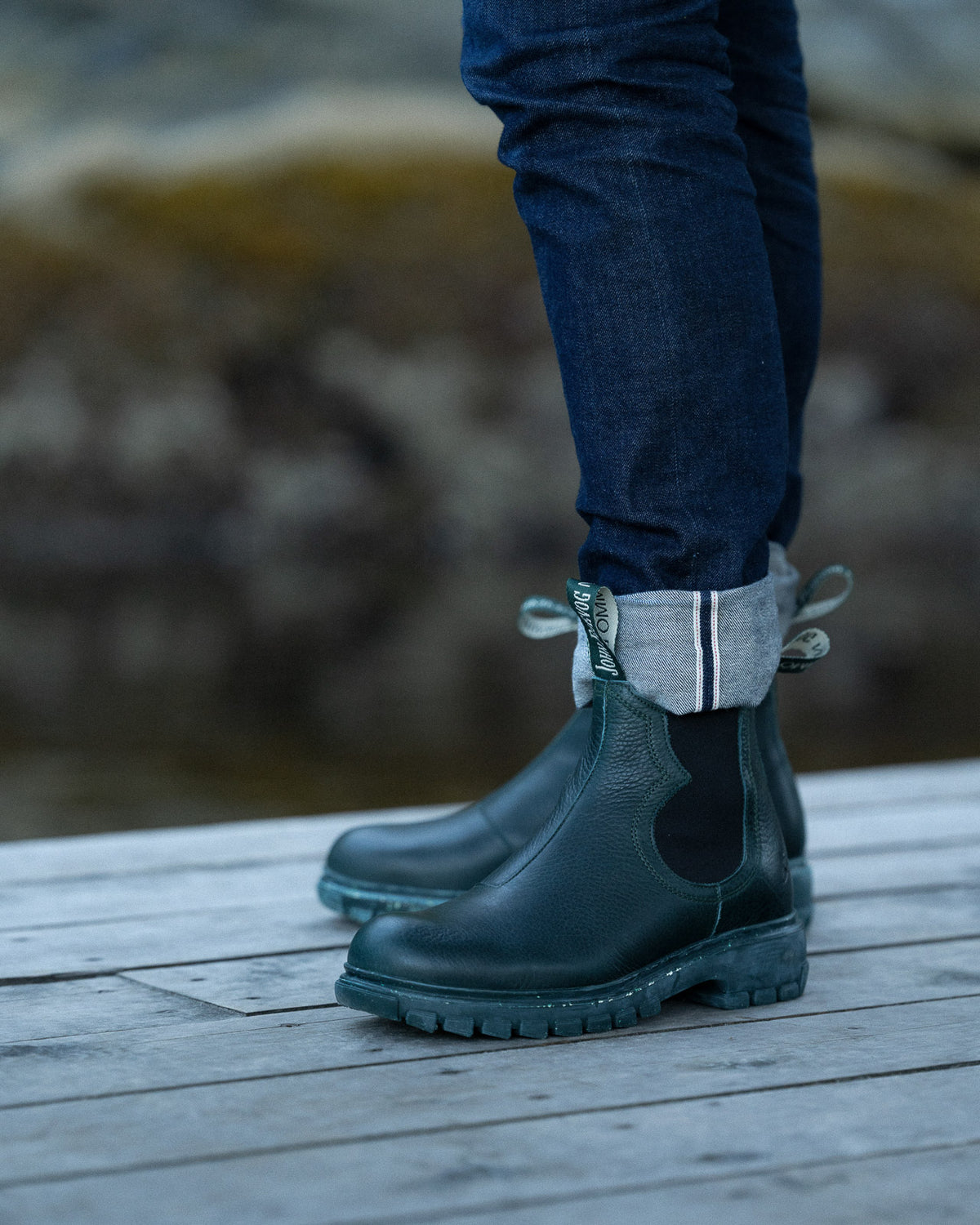 a man wearing green boots standing on a dock