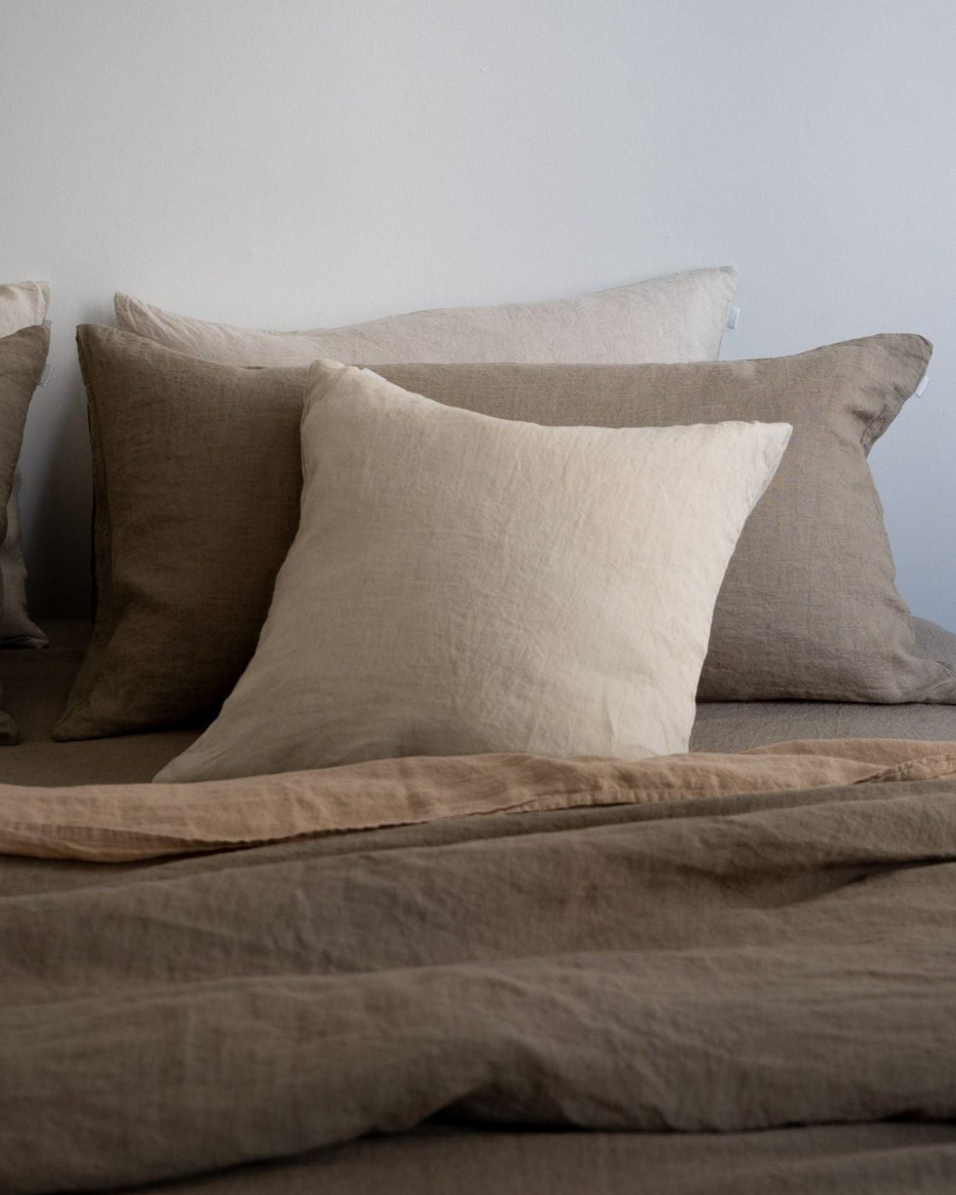 Brown bedding set with pillows on a bed against a light gray wall.