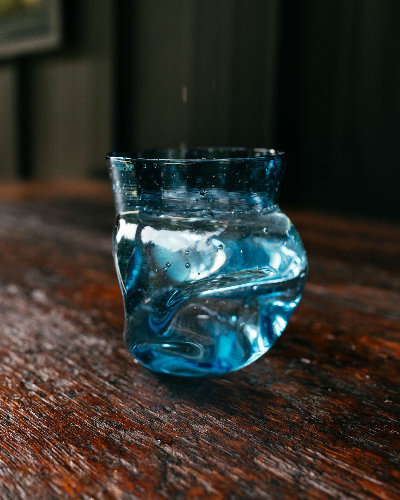 a blue glass full of water on a wooden counter
