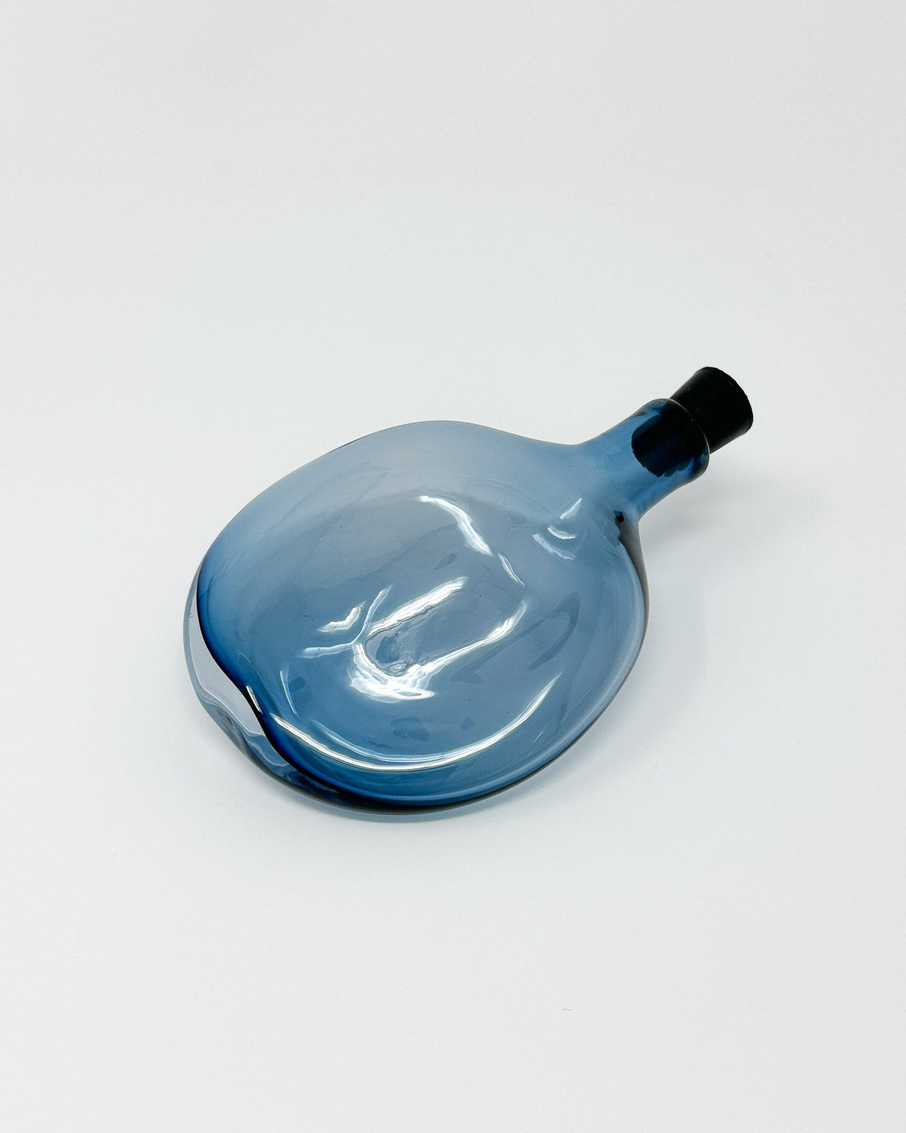 Blue glass flask from Goodbeast with black stopper on a white background