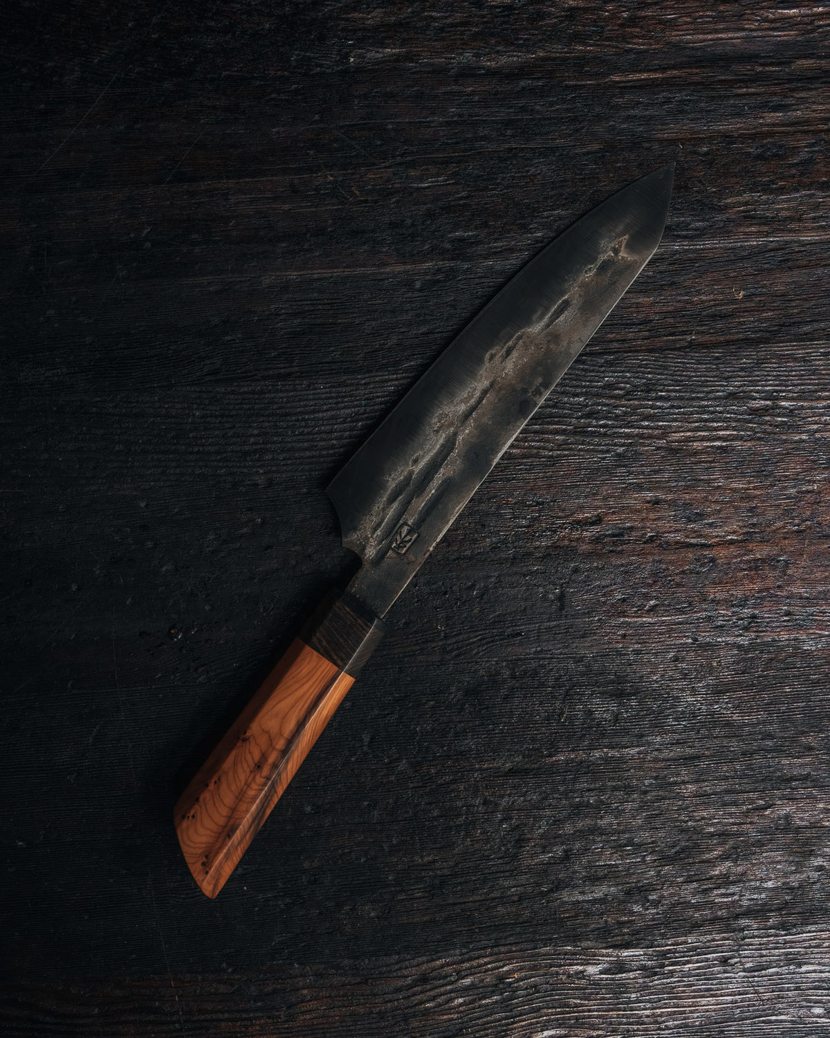 A rustic leechtown blacksmith forged steel knife on a black wooden background