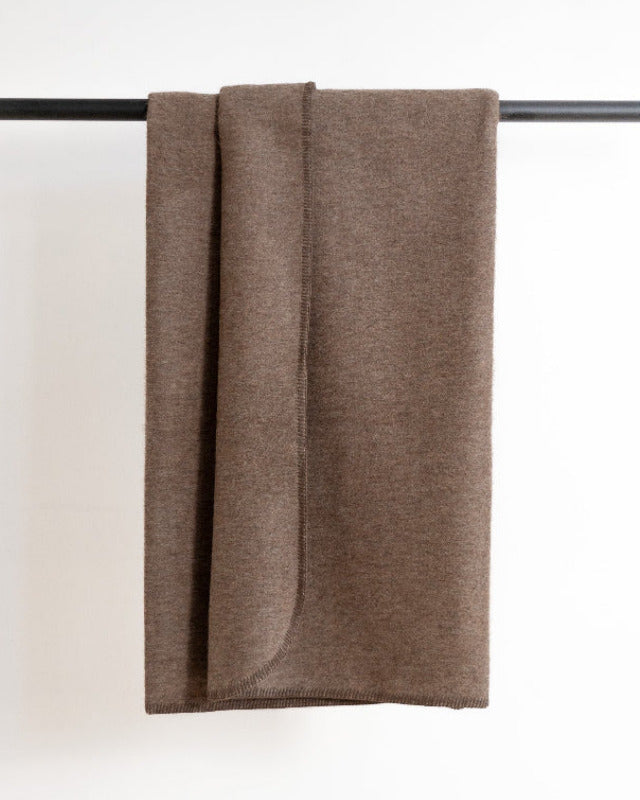 Brown blanket draped over a black rod on a white background
