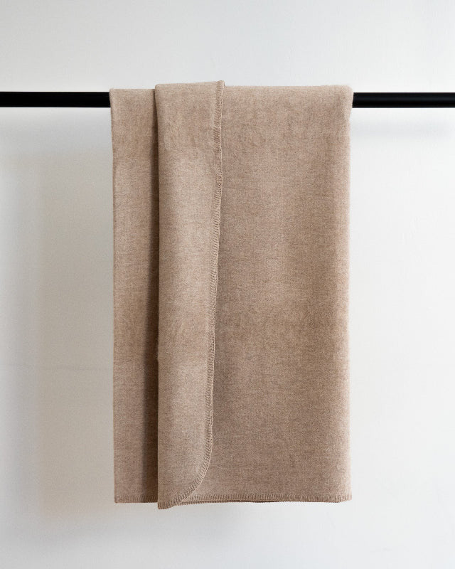 Beige towel hanging on a black rod against a white background