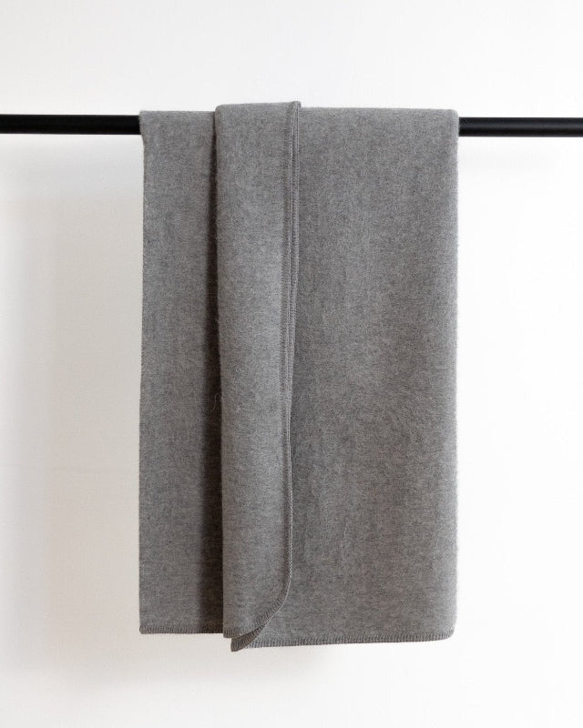 Gray towel draped over a black rod on a white background
