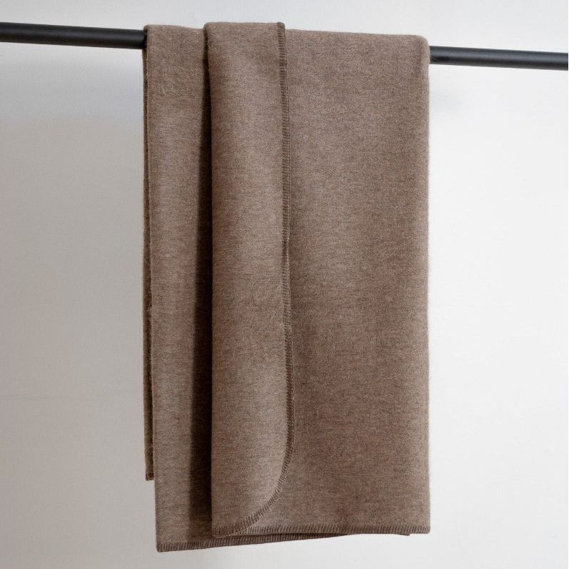 Brown blanket draped over a black rod on a light gray background
