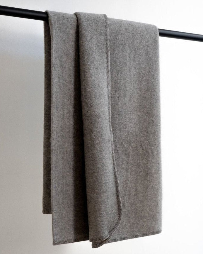 Gray towel draped over a black towel rack on a white background