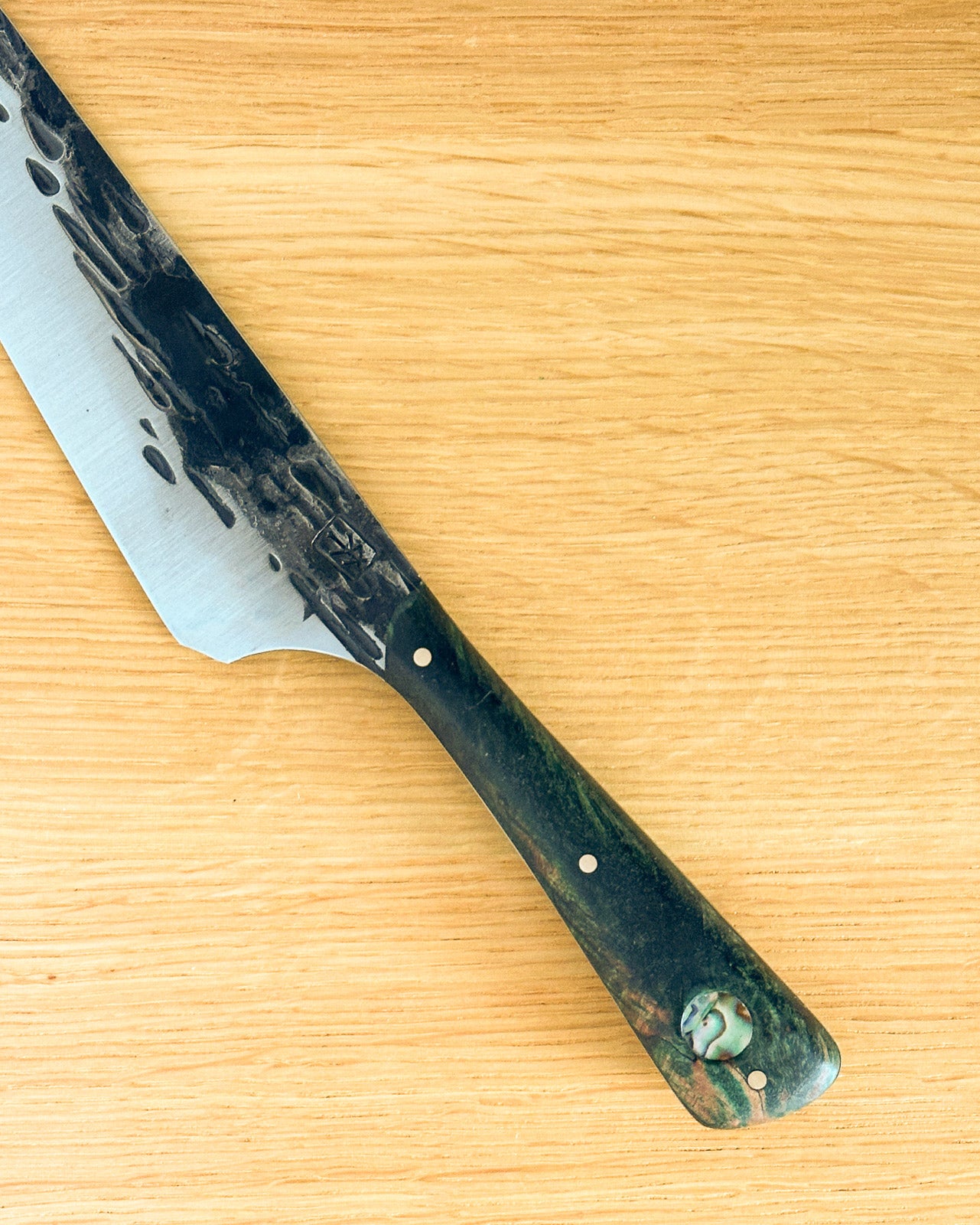 knife with a greenish handle on a wooden surface