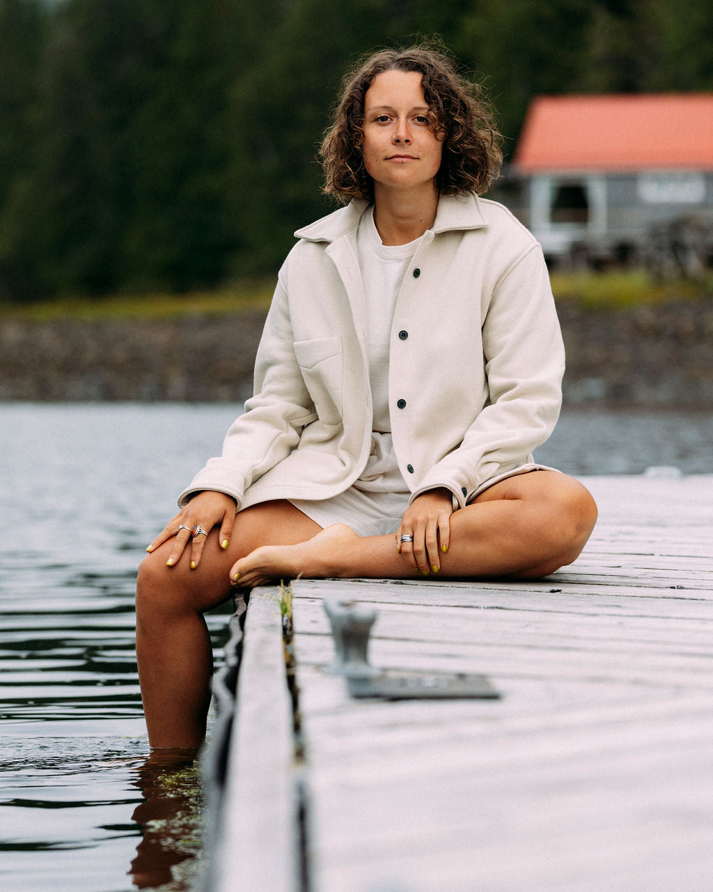 Woman sitting on a dock by the ocean in the Anian circular jersey shirt with a blurred background