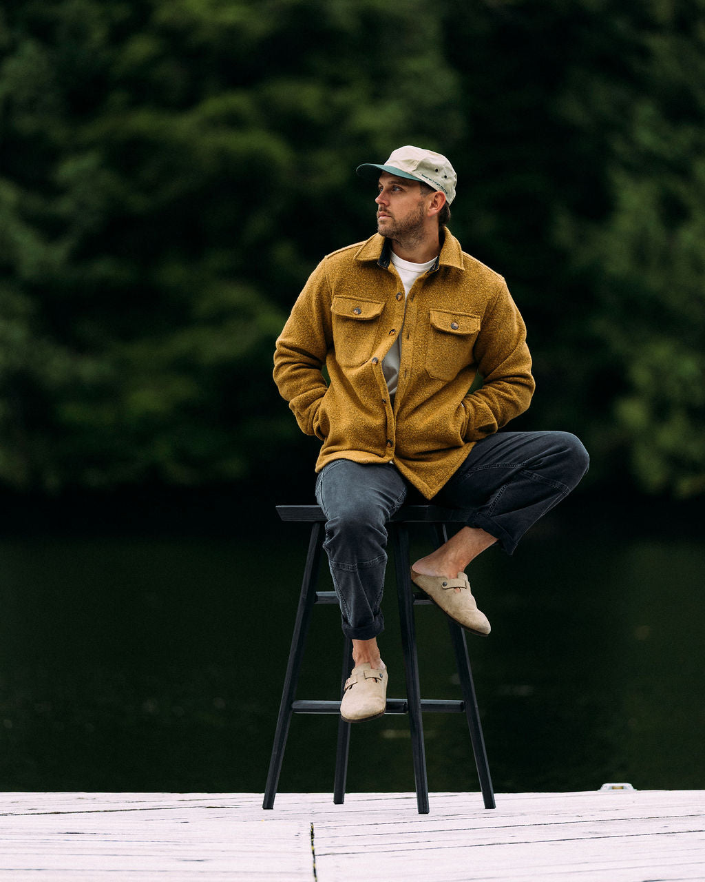 Man sitting on a stool outdoors with a blurred natural background