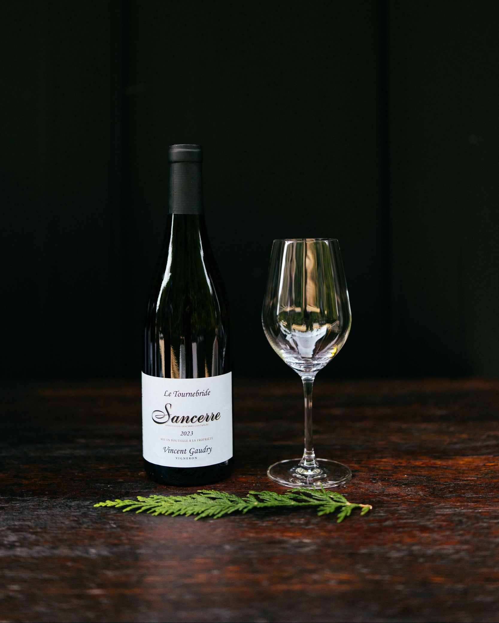 Wine bottle and glass on a dark wooden surface with a black background