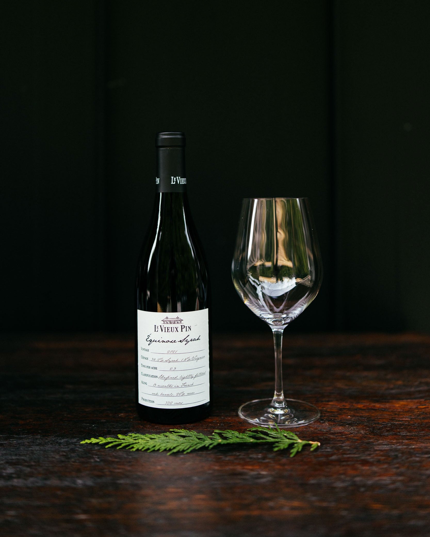Wine bottle and glass on a dark wooden surface with a black background