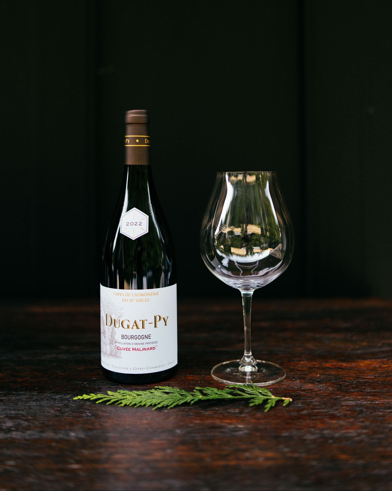 Dugat-Py wine bottle with a glass on a dark wooden surface
