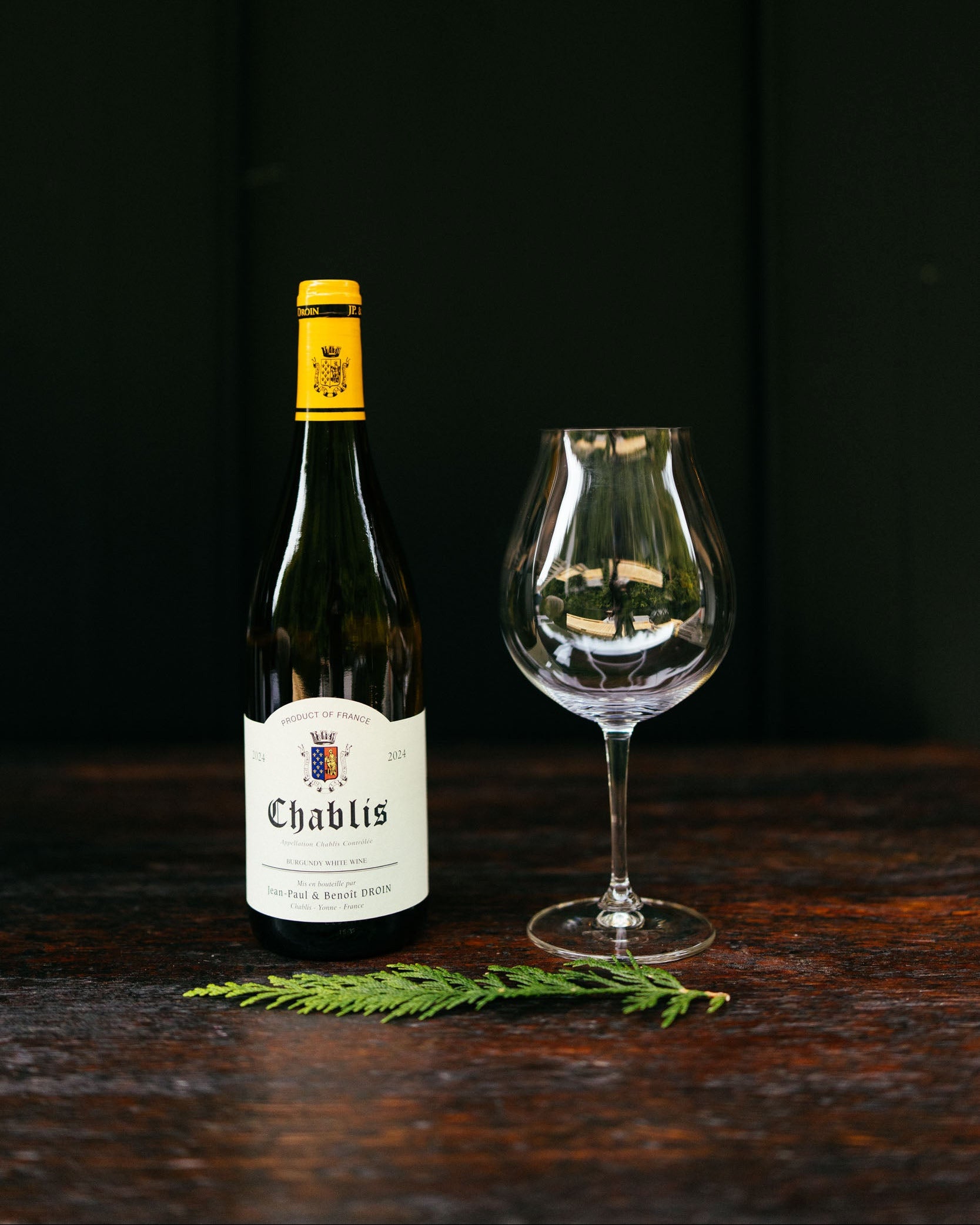 Chablis wine bottle with a glass on a dark wooden surface