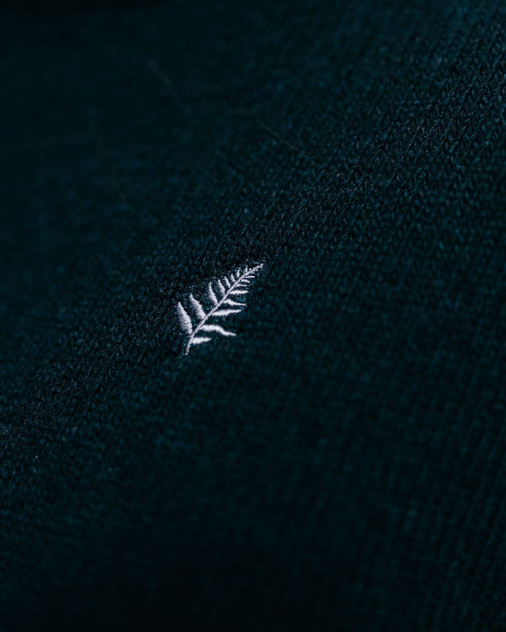 White embroidered leaf design on a dark fabric background