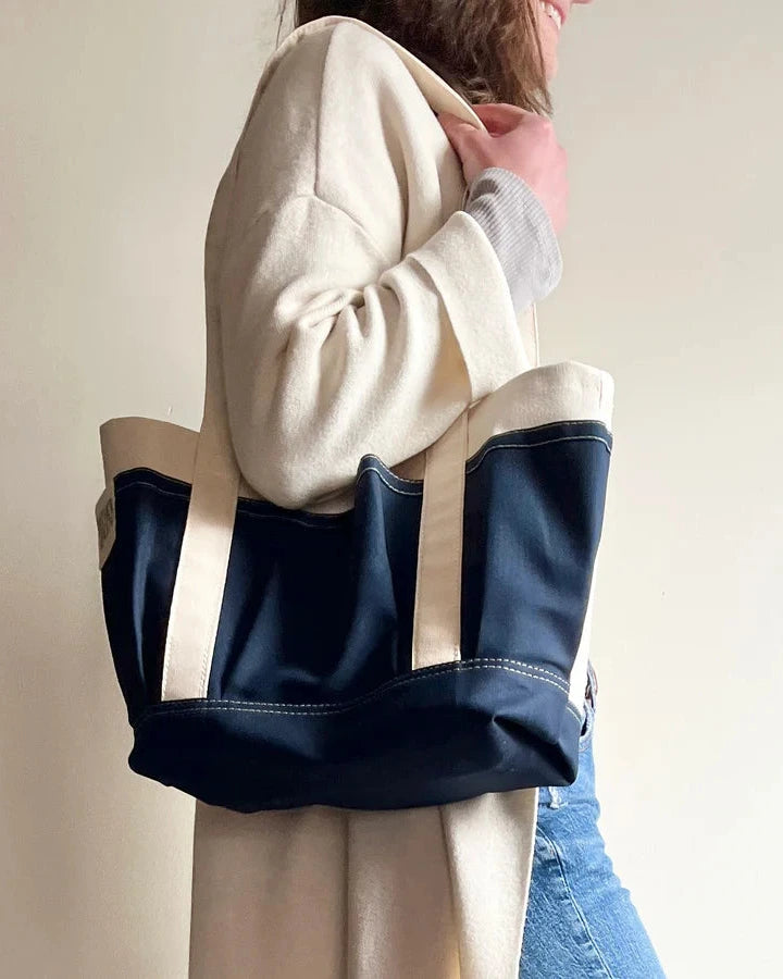 Person wearing a navy Rather green amiga petite tote bag with white handles against a plain background