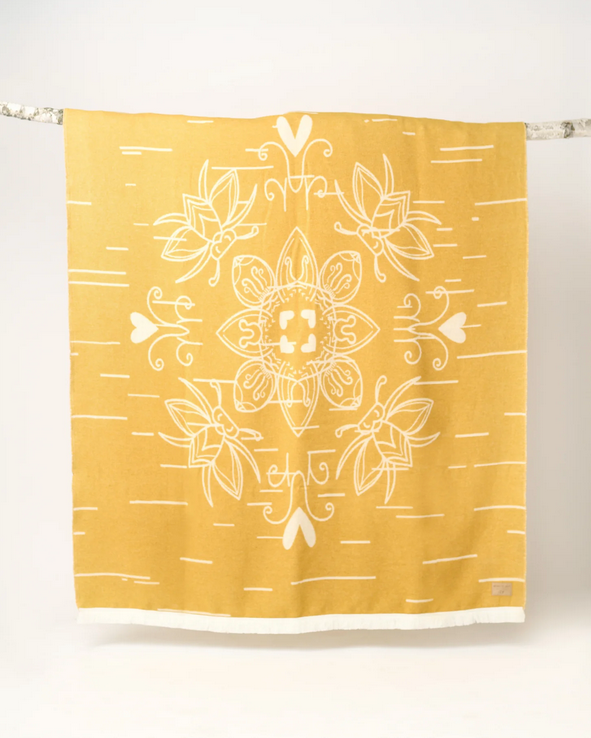 Yellow blanket with white floral patterns hanging on a rack