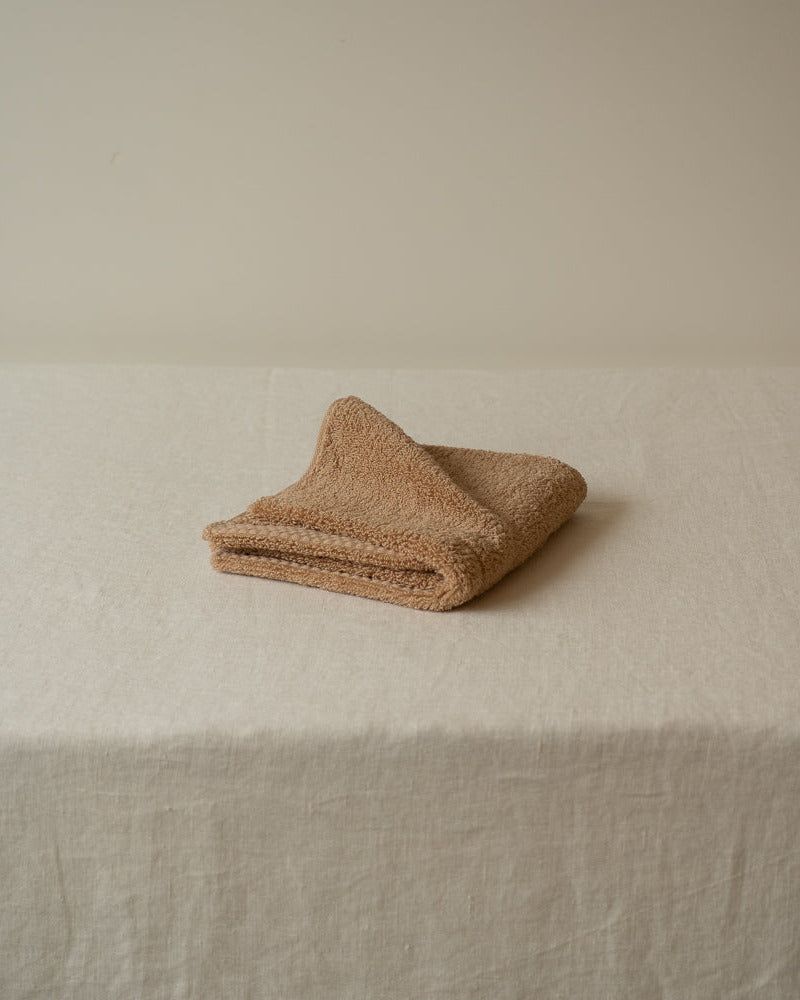 Folded beige towel on a textured surface with a neutral background
