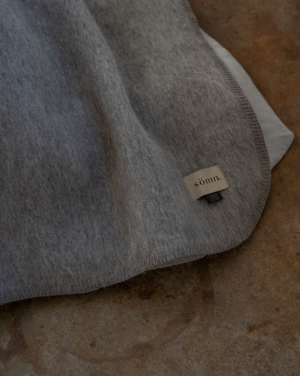 Gray blanket with a brand label on a textured surface